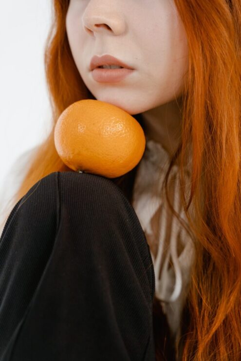 femme rousse avec une orange sous le menton épilation définitive électrolyse menton Essence Yelle Montpellier